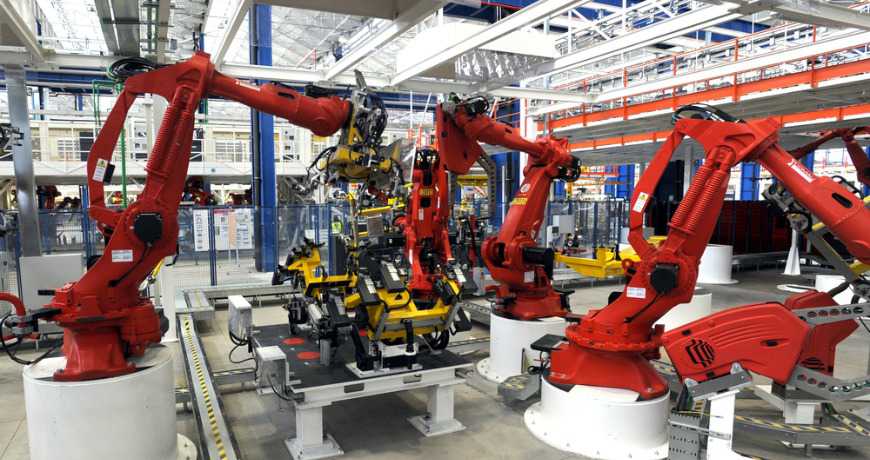 Industrial robotics assembly line with red robotic arms in a steel manufacturing facility
