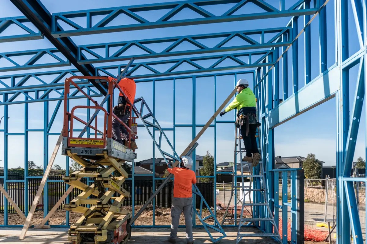 Construction crew assembling the cold-formed steel wall and roof-truss framing of a house